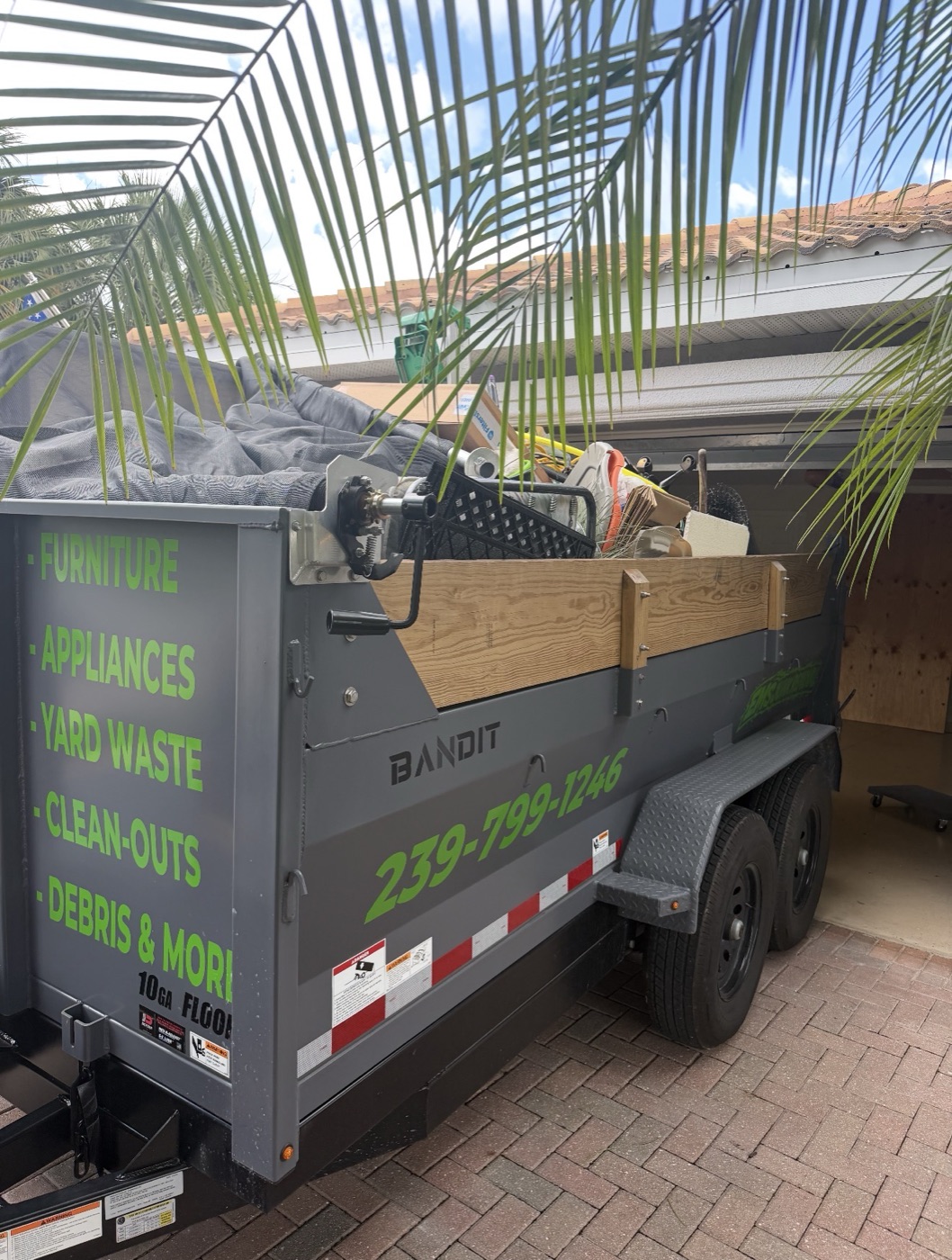 EMS Junk Removal branded dump trailer loaded with junk from a garage cleanout in Southwest Florida